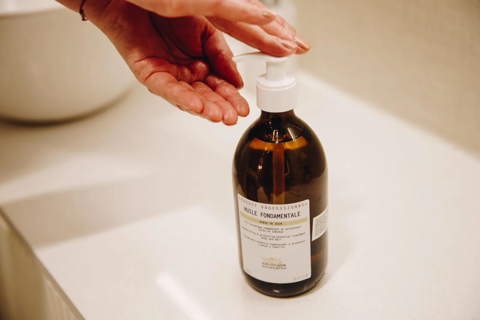 Close up of hands dispensing Biologique Recherche Huile Fondamentale oil at the Miren Medic clinic.