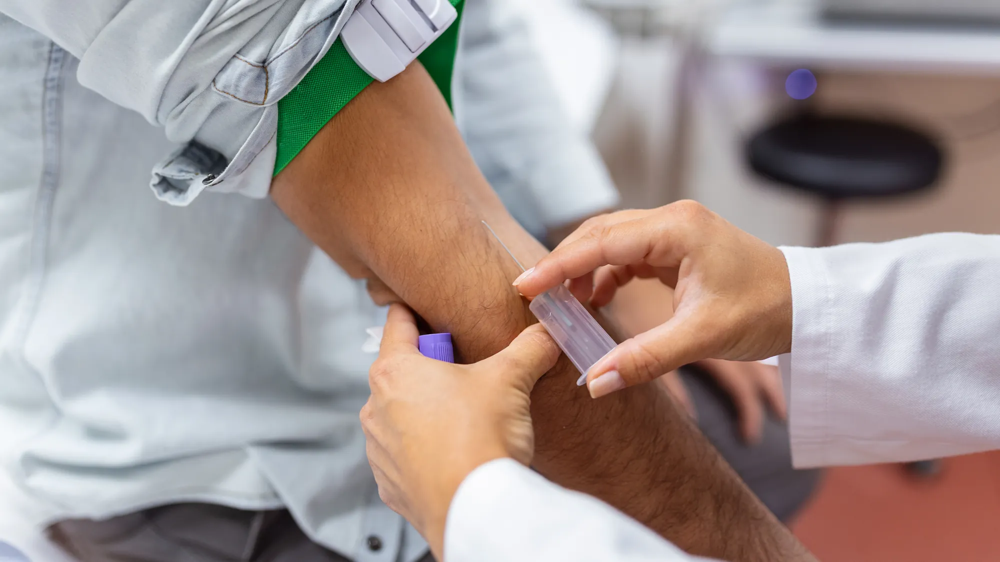 A medical technician placing a tourniquet on a patient's arm before a blood draw