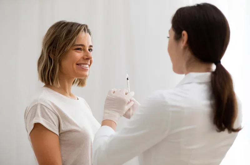 Smiling patient and Mirenmedic doctor preparing for a dermal filler treatment.