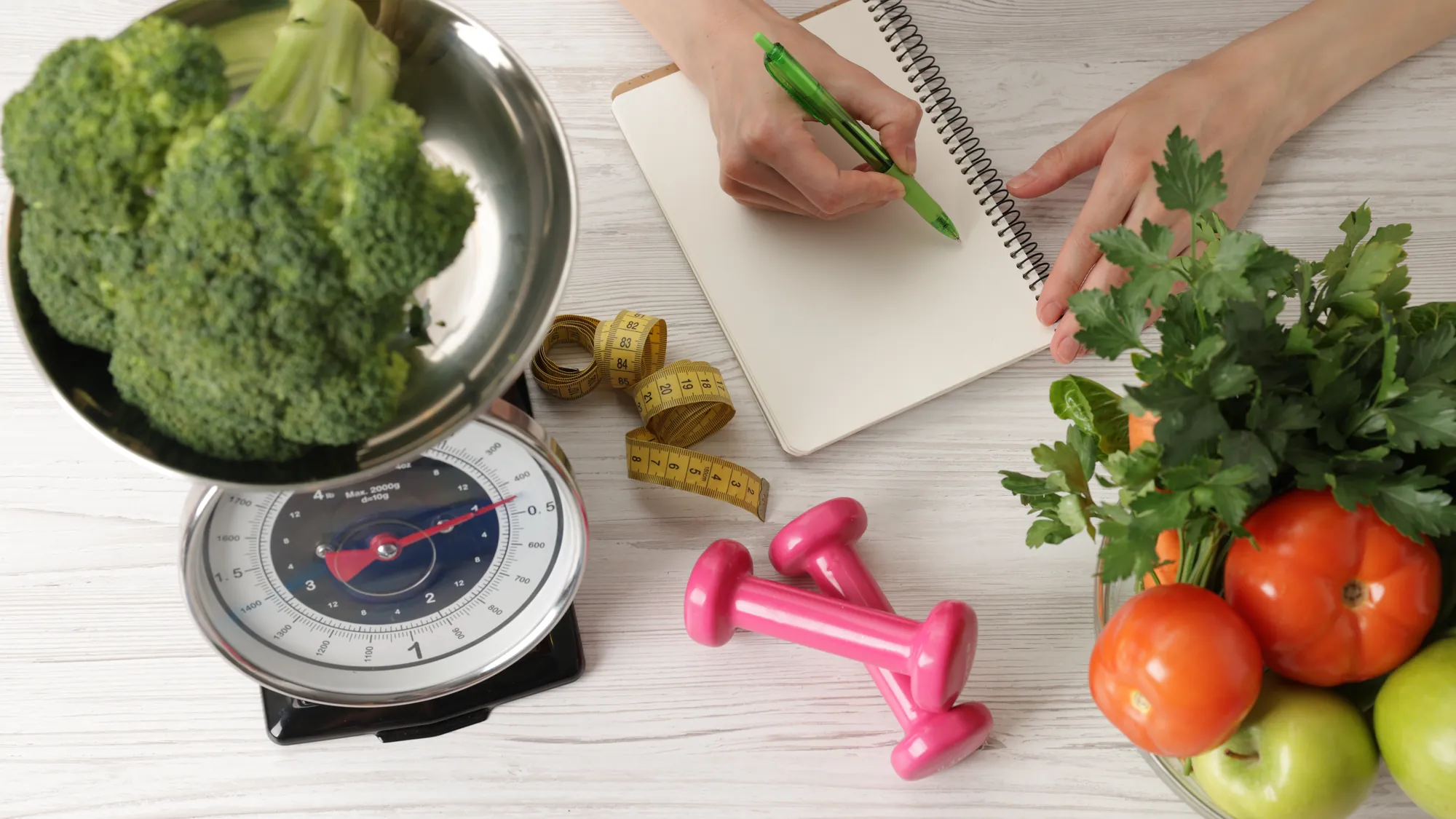 Diet plan on a table with a kitchen scale, vegetables and a tape measure