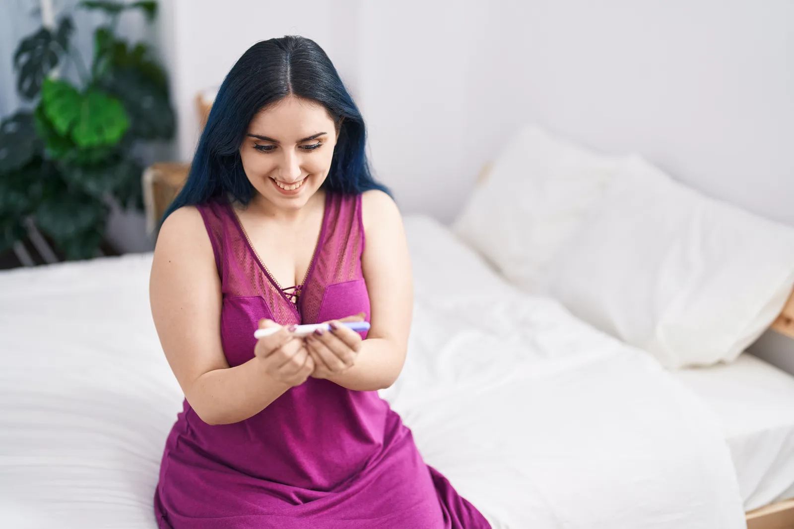 Young smiling woman holding a home pregnancy test