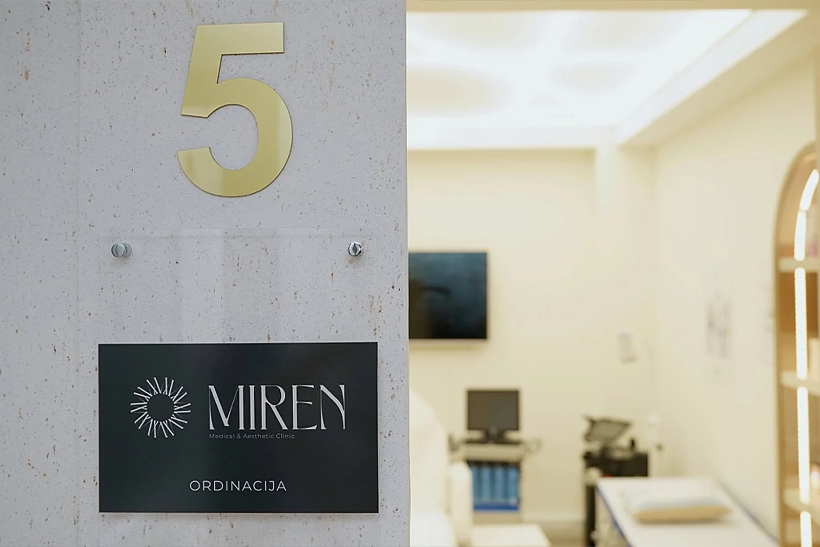 Golden number 5 and the Mirenmedic logo sign at the entrance to a modern treatment room.
