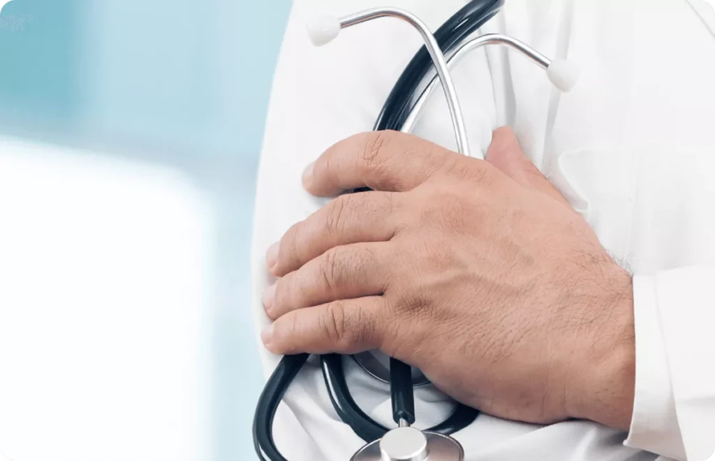 Krupni plan ruke lekara u belom medicinskom mantilu koji drži stetoskop.